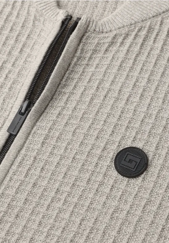 Beige geribbeld breiwerk met zwarte rits en ronde logopatch