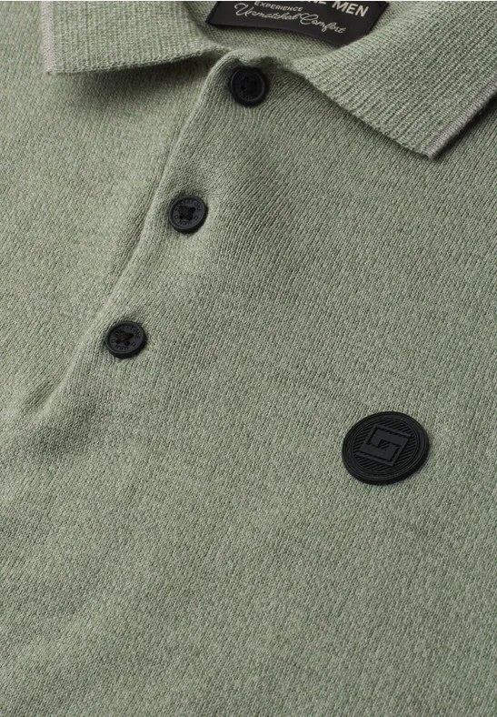 Close-up van een olijfgroen poloshirt met knopenlijst, kraag en ronde, zwarte logopatch.