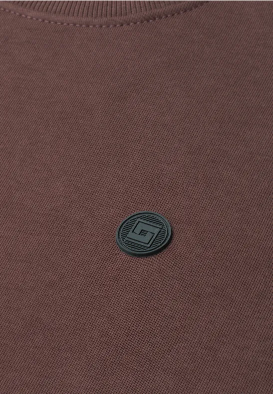 Braunes Sweatshirt mit rundem schwarzem Logo-Button in der Mitte.