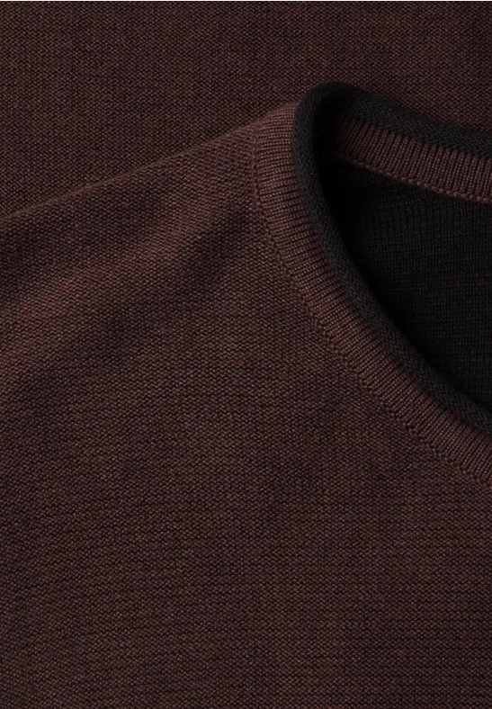 Nahaufnahme eines dunkelbraunen, fein gestrickten Sweaters mit Rundhalsausschnitt.