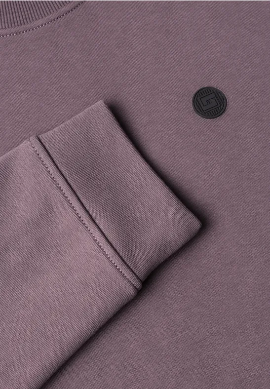 Fliederfarbenes Sweatshirt mit gefaltetem Ärmelbündchen und rundem schwarzem Logo.