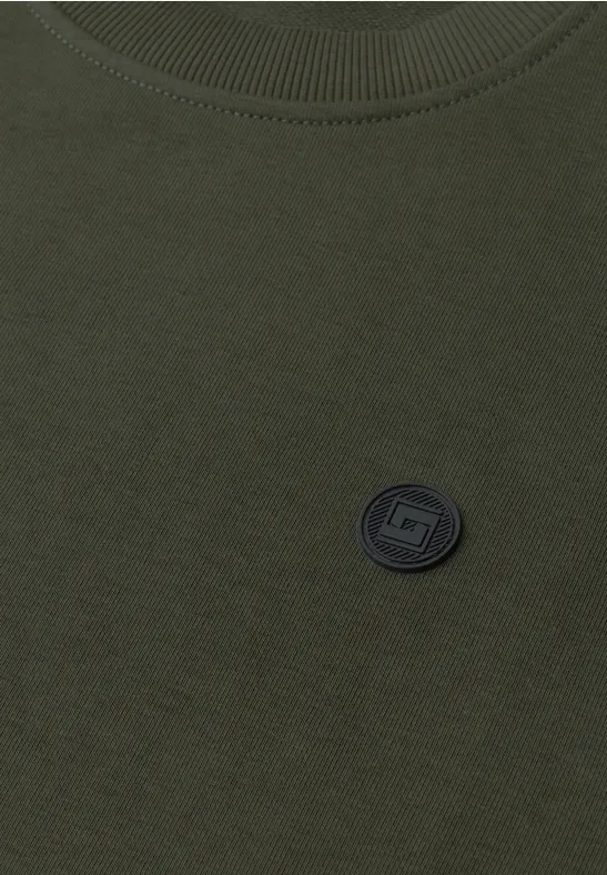 Oliwkowa koszulka z okrągłym dekoltem i czarnym okrągłym logo na piersi.