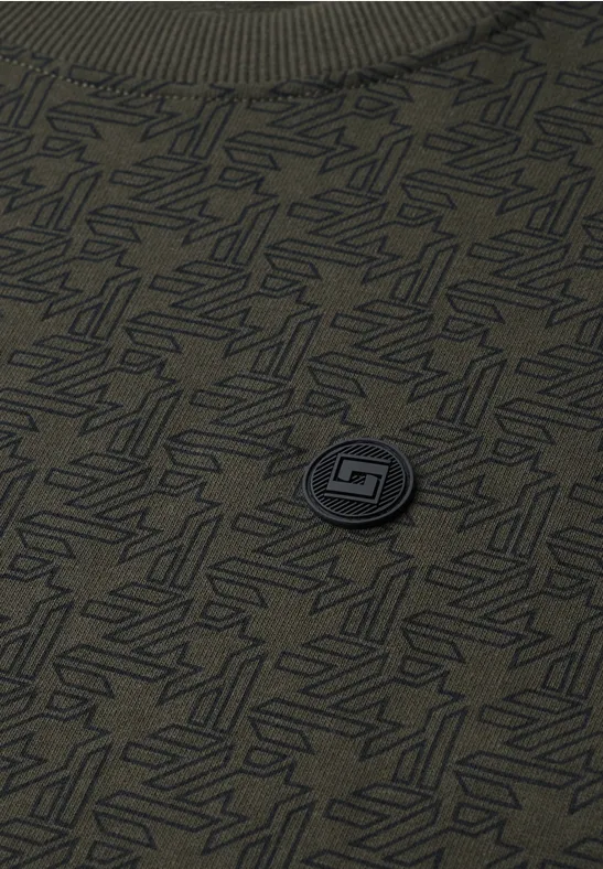 Grünes T-Shirt mit dezentem Allover-Muster und runder Logo-Plakette in der Mitte.