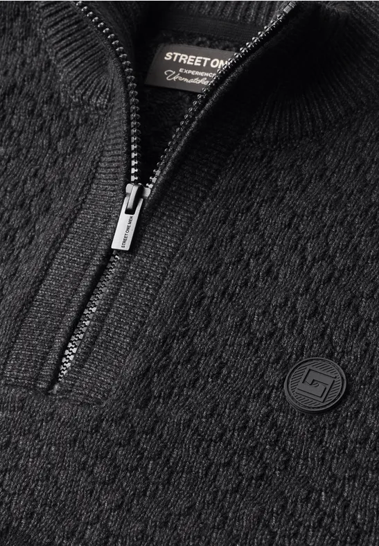 Schwarzer Strickpullover mit halbem Reißverschluss und Logo-Patch.