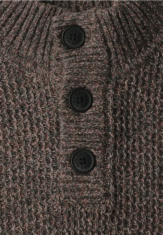 Nahaufnahme eines braunen, grob gestrickten Pullovers mit Stehkragen und drei schwarzen Knöpfen.