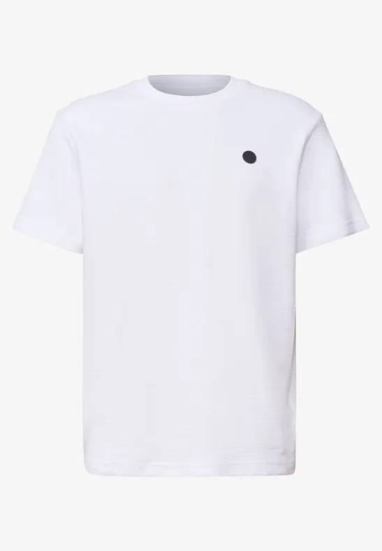 Weißes T-Shirt mit kleinem schwarzem Punkt auf der linken Brustseite.