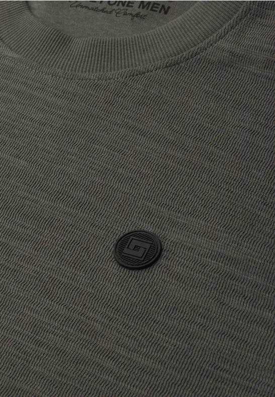 Nahaufnahme eines grauen T-Shirts mit kleinem, rundem Logo auf der Brust.