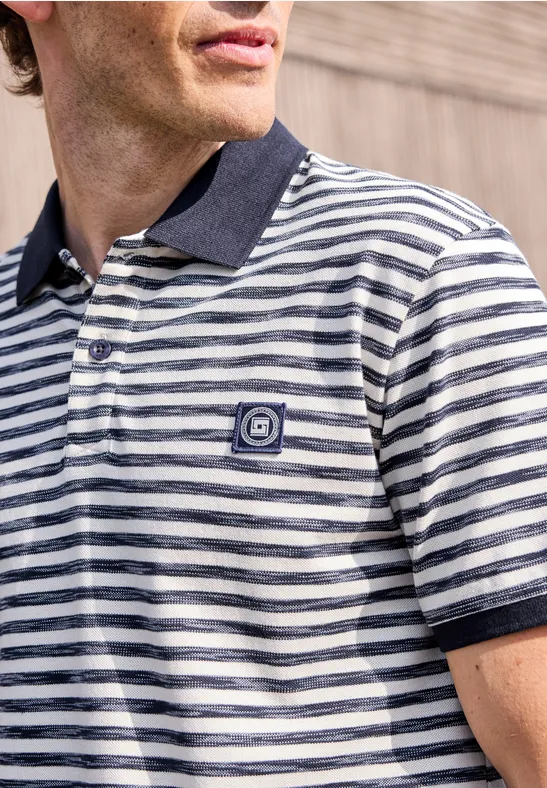 Mann trägt gestreiftes Poloshirt in Weiß und Dunkelblau mit Logo auf der Brust