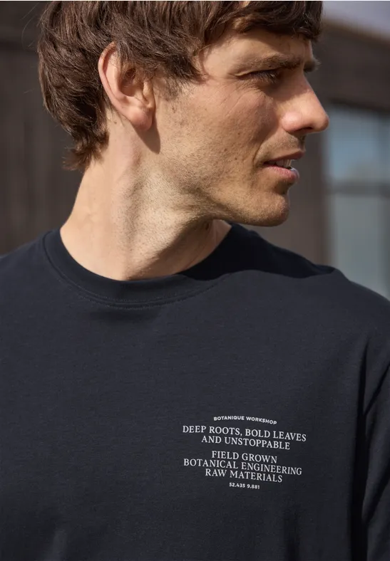 Een man draagt een donkerblauw T-shirt met witte opdruk op de borst.