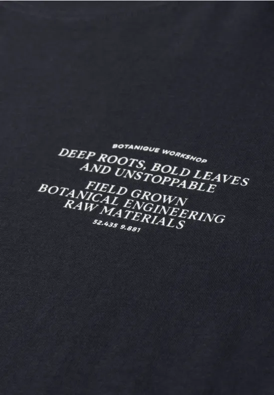 Zwart T-shirt met witte tekst over botanische groei: diepe wortels en stevige bladeren.