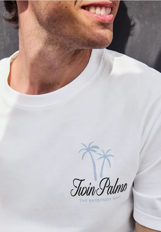 Mann im weißen T-Shirt mit Logo 'Twin Palms' und zwei Palmen als Grafik auf der Brust.