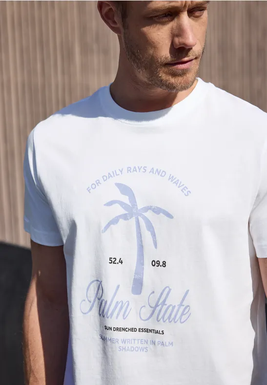 Een man draagt een wit t-shirt met blauwe palmprint en tekst voor een houten achtergrond.