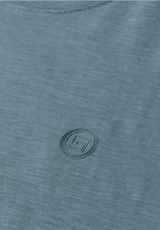 Nahaufnahme eines hellgrünen T-Shirts mit dezentem, rundem Logoaufdruck auf der Brust.