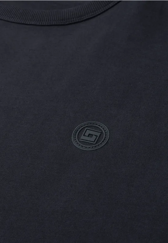 Czarny T-shirt z dyskretnym, okrągłym logo na piersi.
