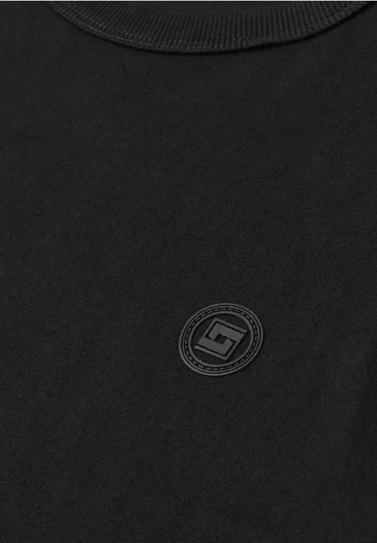 Schwarzes T-Shirt mit rundem, dezentem Logo auf der Brust.