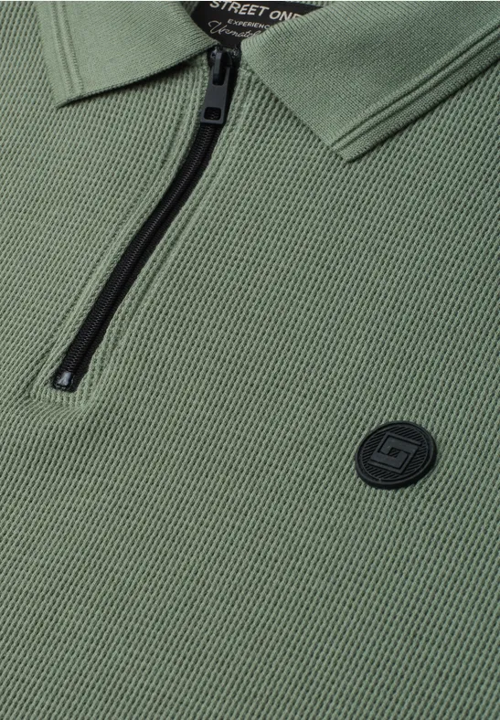 Olivgrünes Polohemd mit Reißverschluss am Kragen und rundem Logo-Patch.