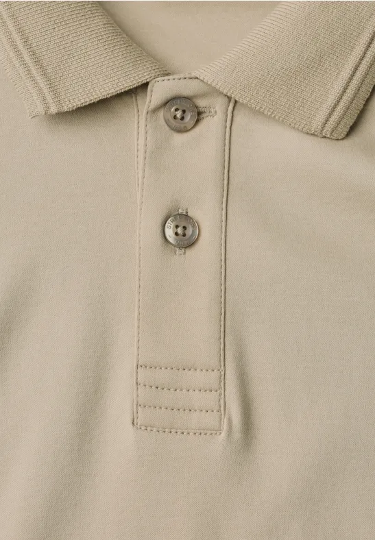 Nahaufnahme eines beigen Poloshirts mit Kragen und zwei Knöpfen.