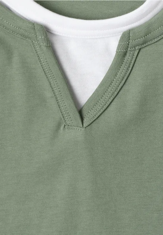 Nahaufnahme eines grünen T-Shirts mit V-Ausschnitt und einem weißen Innenlayer.