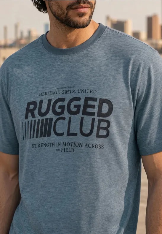 Mann trägt ein hellblaues T-Shirt mit 'Rugged Club'-Aufdruck vor einer Stadt-Silhouette