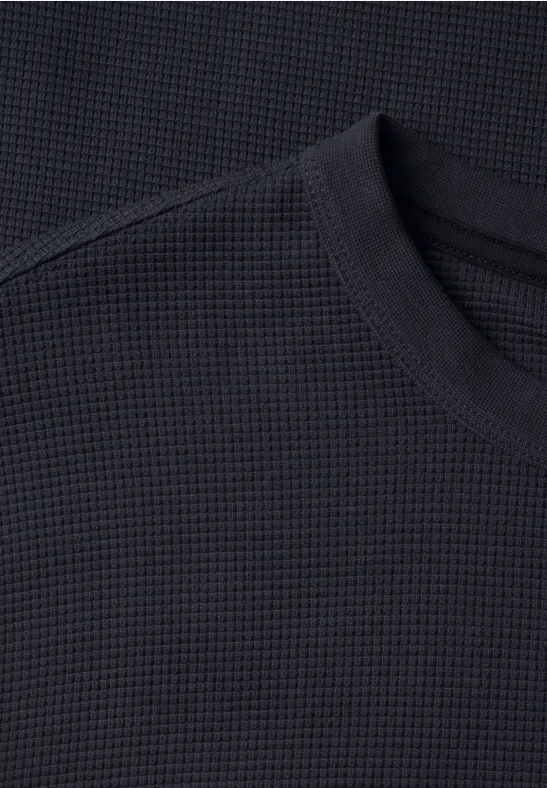 Nahaufnahme eines schwarzen Rundhals-Shirts mit Waffelstrickstruktur.