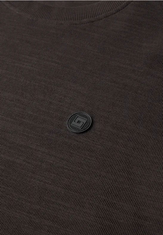 Dunkelbraunes T-Shirt mit kleinem schwarzem runden Emblem in der Mitte der Brust.