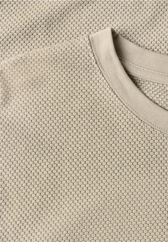Close-up eines beigen T-Shirts mit feiner Wabenstruktur.