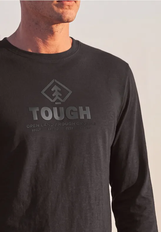 Homme portant un t-shirt noir à manches longues, inscription « TOUGH » et logo flèche stylisée