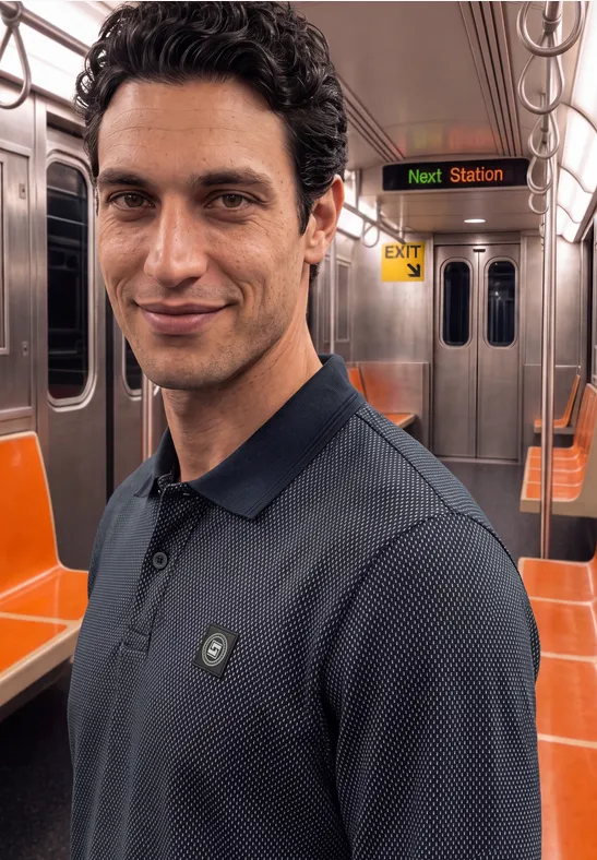 Ein lächelnder Mann mit dunkelblauem Hemd in einem U-Bahn-Wagen mit orangenen Sitzen.