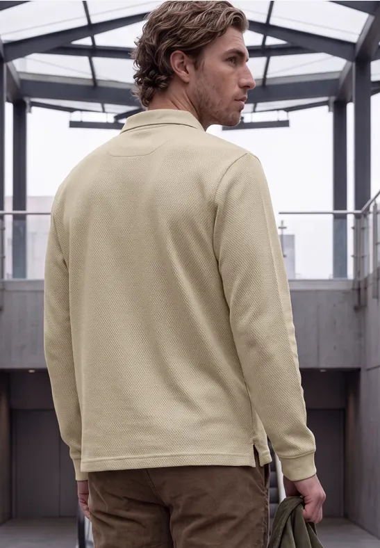 Ein Mann in beige Jacke von hinten in einem modernen Gang mit Glasdach, blickt über die Schulter.