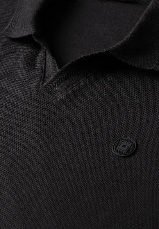 Polo noir avec col en V et petit écusson rond de logo sobre sur la poitrine.