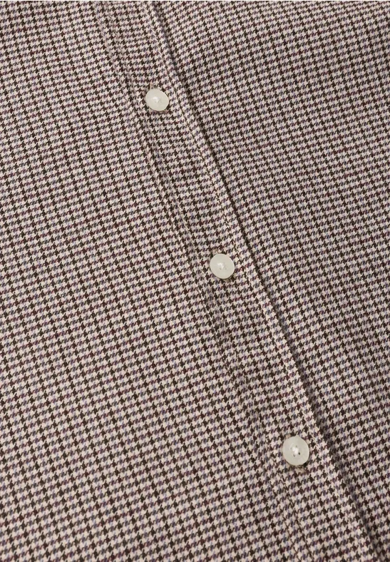 Gros plan d’une chemise à petits carreaux marron et blanc avec des boutons blancs.