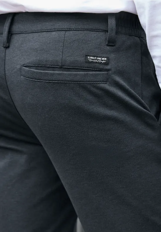 Achteraanzicht van een persoon in donkergrijze pantalon met achterzak en logopatch