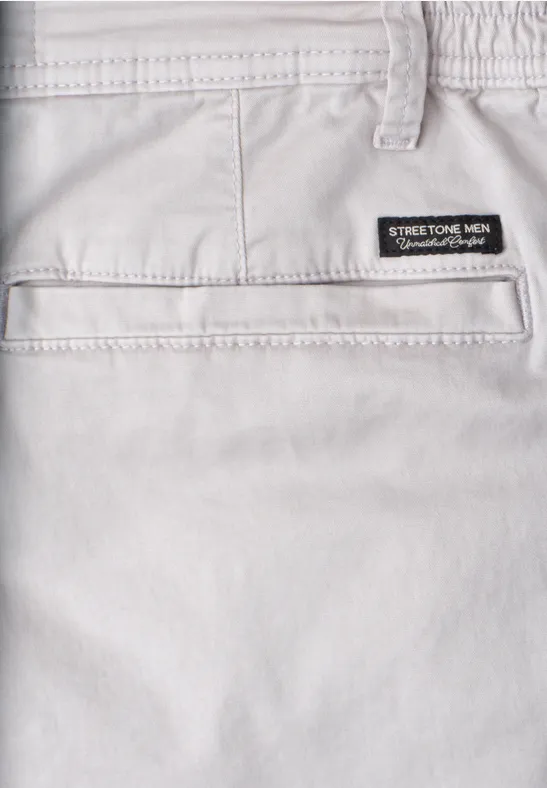 Zbliżenie jasnoszarych elastycznych spodni z tylną kieszenią i metką na pasie