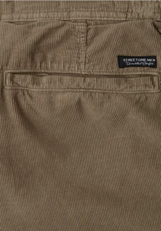 Nahaufnahme einer braunen Stoffhose mit Gesäßtasche und kleinem Label.