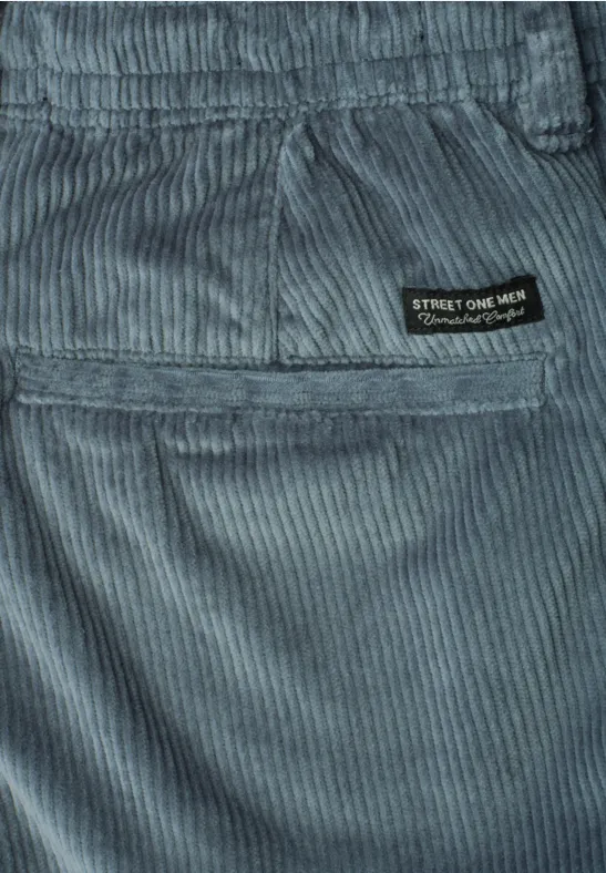 Close-up einer graublauen Cordhose mit Gesäßstasche und schwarzem Markenlabel