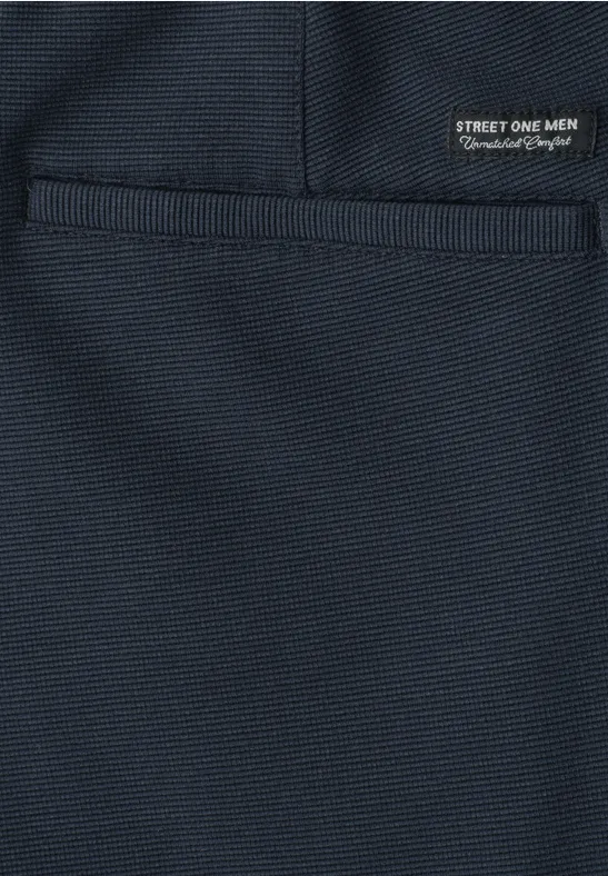 Dunkelblaue Stoffoberfläche mit aufgesetzter Tasche und kleinem schwarzen Etikett 'STREET ONE MEN'.