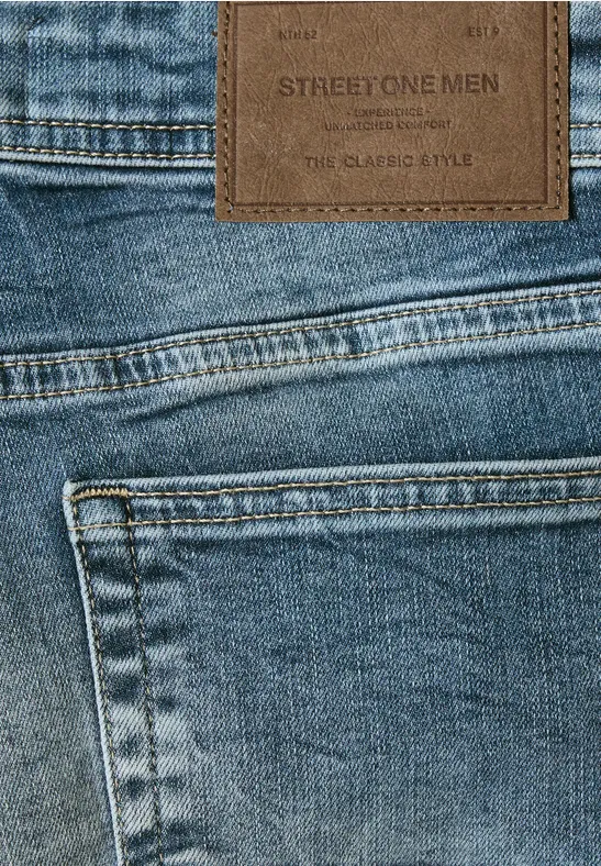 Nahaufnahme von blauer Jeans mit Tasche und braunem Lederpatch 'STREET ONE MEN' am Bund.