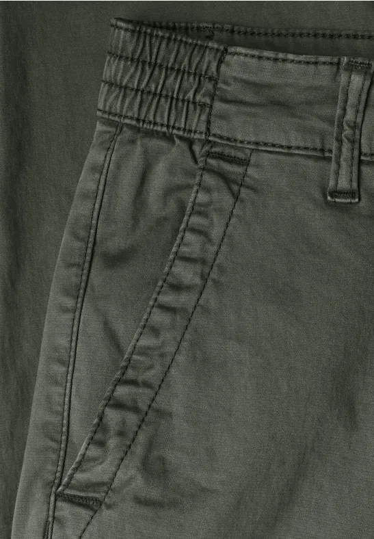 Nahaufnahme einer dunkelgrünen Hose mit elastischem Bund, Gürtelschlaufen und seitlicher Eingrifftasche.
