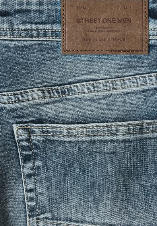 Nahaufnahme einer blauen Jeanshosentasche mit braunem Leder-Label 'STREET ONE MEN'.