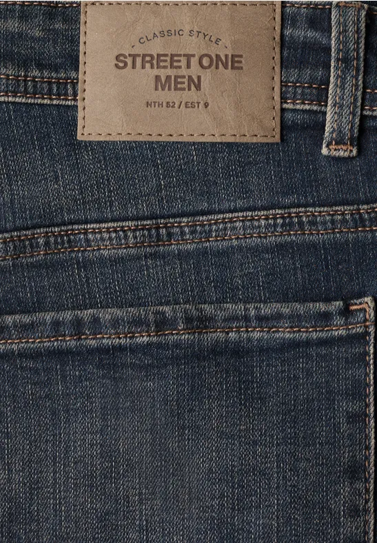 Nahaufnahme einer Herrenjeans mit Street One Men Lederpatch am Bund und sichtbarer Gesäßtasche.