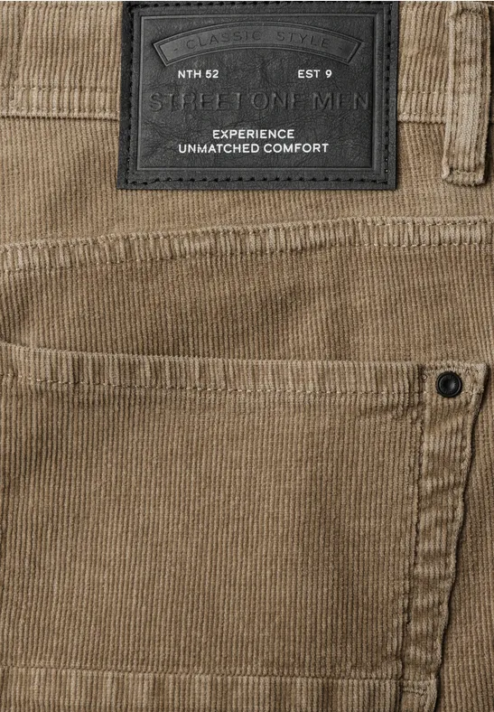 Nahansicht einer beigefarbenen Cordhose mit Label und seitlicher Tasche.