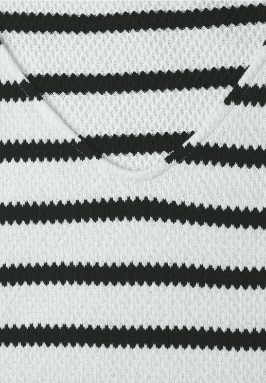 Nahaufnahme eines schwarz-weißen, gestreiften Strick-V-Ausschnitt-Pullovers.