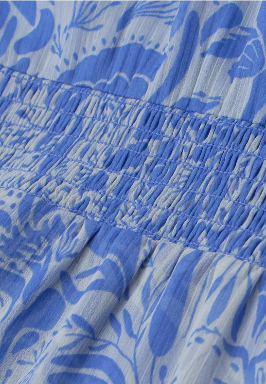 Close-up van lichtblauw, wit bloemendessin op geplooide, gesmokte stof met fijne textuur.