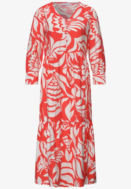 Koraalrode lange jurk met wit abstract patroon, lange mouwen, V-hals en geplooide rok