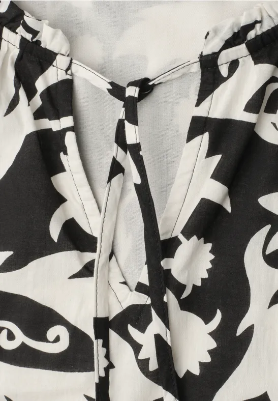 Schwarz-weiß gemustertes Oberteil im Boho-Stil mit V-Ausschnitt und dekorativer Kordel zum Schnüren.