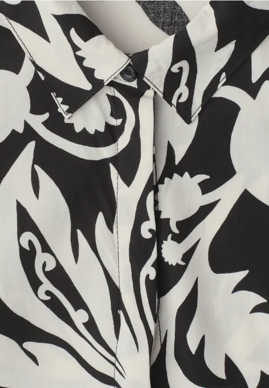 Zwart-wit stof met abstract bloemmotief en zichtbare knopenlijst.