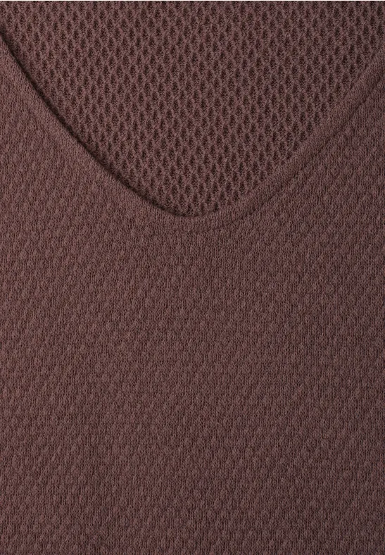 Gros plan d’un haut en maille marron à col en V avec motif ajouré.