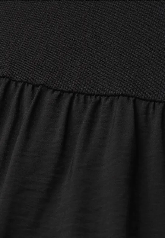 Gros plan sur un tissu noir, partie supérieure côtelée et bas froncé