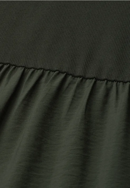 Vue en gros plan d’un vêtement vert olive avec couture, tissu côtelé en haut et lisse en bas