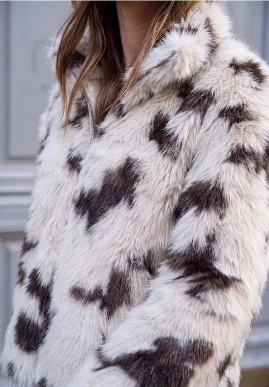 Weiße flauschige Kunstpelzjacke mit dunkelbraunen Herzmustern.